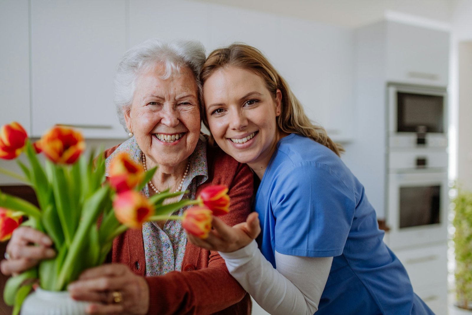 Senior woman and nurse with tulip bouquet.